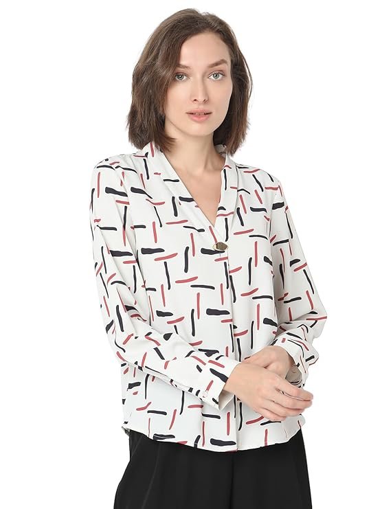 Woman wearing a light blue bohemian print V-neck top with button detailing on the long sleeves and cuffs.